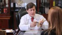 dr. paul mccormick with patient in his office holding model of a spine